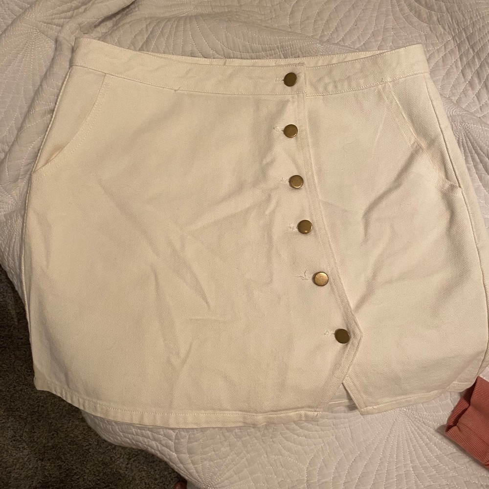 White skirt. Gold buttons